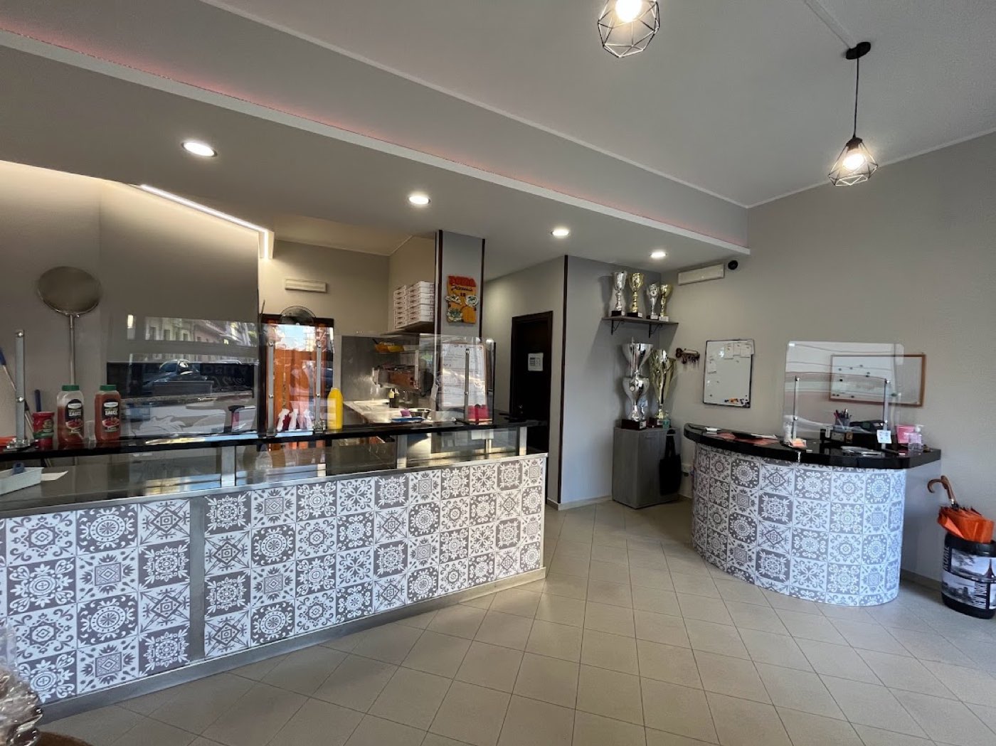 Il banco della pizzeria rivestito in maiolica siciliana con i trofei esposti